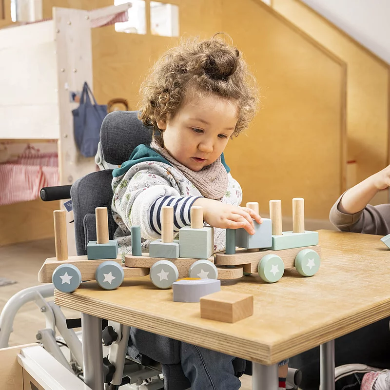 Kind sitzt am Tisch und spielt mit Spielzeug